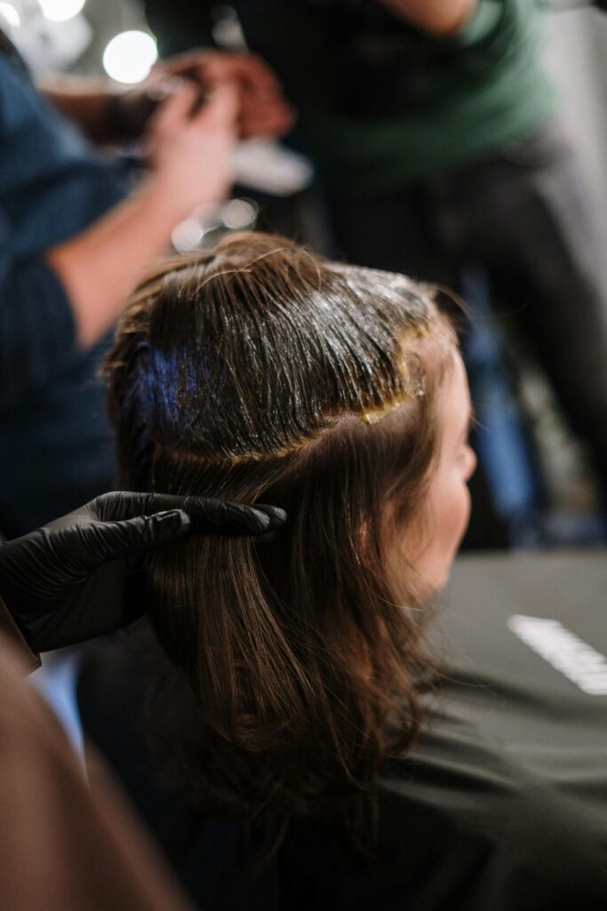 Woman receiving hair coloring treatment in a modern salon setting.